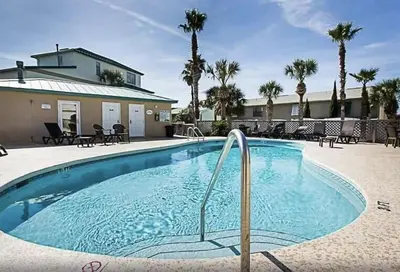 a swimming pool with chairs and a house at The Palms A6 in Panama City Beach