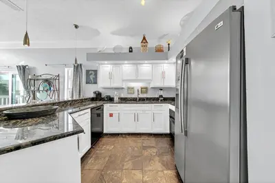 a kitchen with white cabinets and a stainless steel refrigerator at The Palms A6 in Panama City Beach