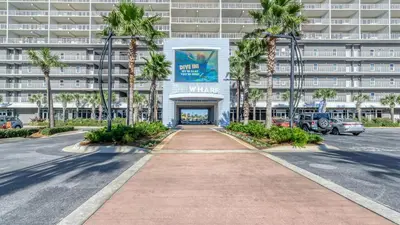 a walkway in front of a building with palm trees at Laketown Wharf #626 by Nautical Properties in Panama City Beach