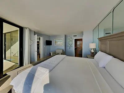 a large white bed in a bedroom with blue walls at Edgewater Tower Iii 504 in Panama City Beach
