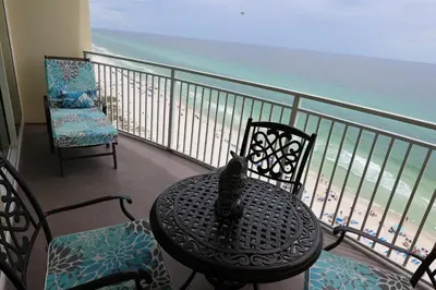 a cat sitting on a table on a balcony overlooking the beach at AQUA 1504 Beachfront condo with Free Beach Chairs in Panama City Beach