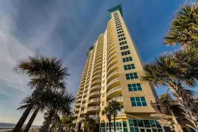 a tall building with palm trees in front of it at AQUA 1504 Beachfront condo with Free Beach Chairs in Panama City Beach