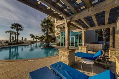 a swimming pool with blue chairs next to a building at AQUA 1504 Beachfront condo with Free Beach Chairs in Panama City Beach