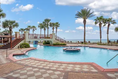 a large swimming pool with palm trees and a boat at Shores Of Panama #0323 in Panama City Beach