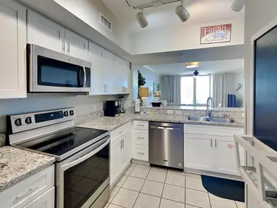 a large kitchen with white cabinets and a microwave at Emerald Beach #936 in Panama City Beach