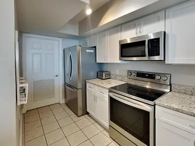 a kitchen with white cabinets and stainless steel appliances at Emerald Beach #936 in Panama City Beach