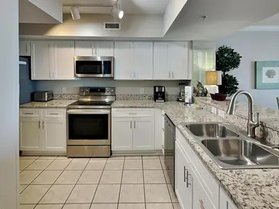 a kitchen with white cabinets and stainless steel appliances at Emerald Beach #936 in Panama City Beach