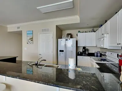 a kitchen with a sink and a refrigerator at Tidewater Beach Resort #1306 - Beach Bliss in Panama City Beach