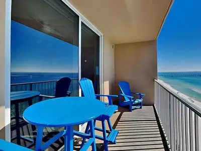 a balcony with tables and chairs and a view of the ocean at Tidewater Beach Resort #1306 - Beach Bliss in Panama City Beach