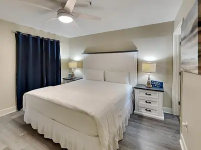 a bedroom with a large white bed and blue curtains at Tidewater Beach Resort #1306 - Beach Bliss in Panama City Beach