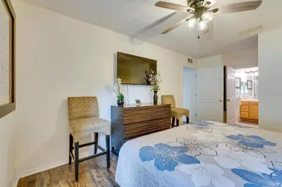 a bedroom with a bed and two chairs and a mirror at PCB Condo with Pool Access 1 Mi to Beach! in Panama City Beach