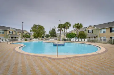a large swimming pool in a courtyard with houses at PCB Condo with Pool Access 1 Mi to Beach! in Panama City Beach