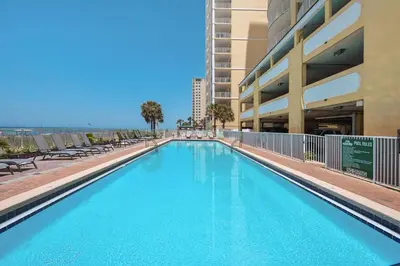 a swimming pool with chairs and a building at Twin Palms 1802 in Panama City Beach
