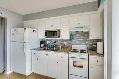 a kitchen with white cabinets and a white refrigerator at Panama City Beach Getaway - Walk to Beaches! in Panama City Beach