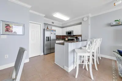 a kitchen with white appliances and white chairs in a room at Tidewater 1113 in Panama City Beach