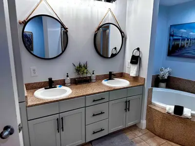 a bathroom with two sinks and a tub and two mirrors at Melan Villa Costal Magic Ocean View in Panama City Beach