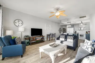 a living room with blue furniture and a clock on the wall at Laketown Wharf #1007 by Nautical Properties in Panama City Beach