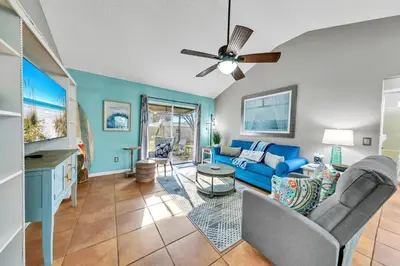 a living room with a blue couch and a ceiling fan at Manatee Summer House in Panama City Beach