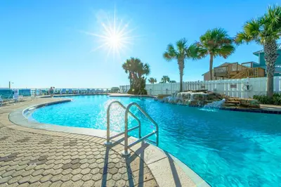 a swimming pool with palm trees and the sun at Majestic Beach Towers 1-2015 in Panama City Beach