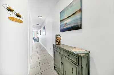 a hallway with a green cabinet and a painting on the wall at Majestic Beach Towers 1-2015 in Panama City Beach