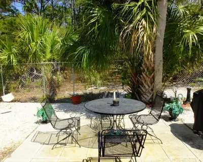 a patio with a table and chairs and palm trees at Venture Out 79 Gulf Loop Comes With Golf Cart in Panama City Beach