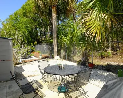 a patio with a table and chairs and a palm tree at Venture Out 79 Gulf Loop Comes With Golf Cart in Panama City Beach