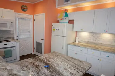 a kitchen with white cabinets and a white refrigerator at Venture Out 41 Gulf Loop 2bd 1ba WITH GOLF CART in Panama City Beach