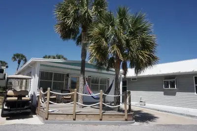 a house with palm trees and a hammock in front of it at Venture Out 41 Gulf Loop 2bd 1ba WITH GOLF CART in Panama City Beach