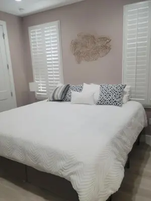a white bed in a bedroom with two windows at Venture Out 600 Seabreeze Dr Comes WITH GOLF CART in Panama City Beach