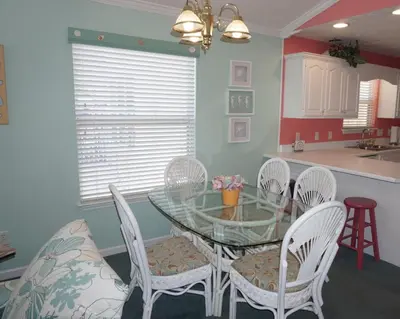 a dining room with a glass table and white chairs at Venture Out 402 North Marlin Dr WITH GOLF CART in Panama City Beach