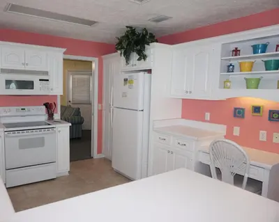 a kitchen with white cabinets and a white refrigerator at Venture Out 402 North Marlin Dr WITH GOLF CART in Panama City Beach