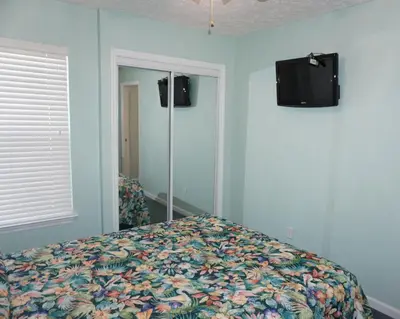 a bedroom with a bed and a tv on the wall at Venture Out 402 North Marlin Dr WITH GOLF CART in Panama City Beach
