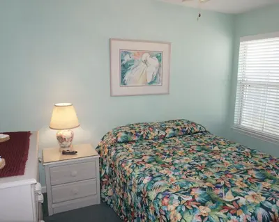 a bedroom with a bed and a night stand with a lamp at Venture Out 402 North Marlin Dr WITH GOLF CART in Panama City Beach