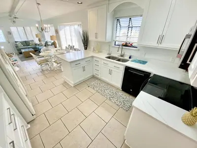 a kitchen with white cabinets and a living room at Venture Out 332 Lagoon Ln WITH 2 GOLF CARTS in Panama City Beach