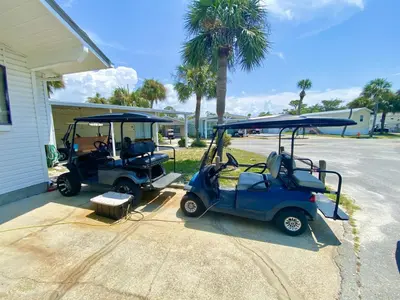 two golf carts are parked next to a building at Venture Out 332 Lagoon Ln WITH 2 GOLF CARTS in Panama City Beach