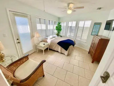 a bedroom with a bed and a chair and windows at Venture Out 332 Lagoon Ln WITH 2 GOLF CARTS in Panama City Beach