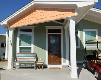 a small green house with a wooden door and a porch at Venture Out 152 Gulf Loop With Golf Cart in Panama City Beach