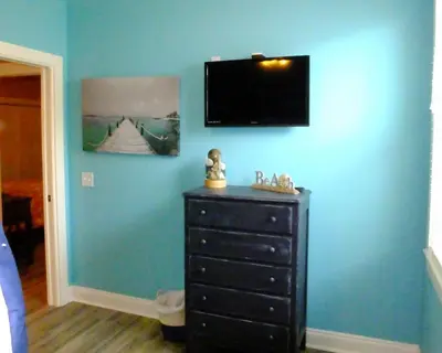 a bedroom with a dresser and a television on a blue wall at Venture Out 152 Gulf Loop With Golf Cart in Panama City Beach