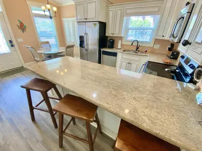 a kitchen with a large marble counter top and chairs at Venture Out 152 Gulf Loop With Golf Cart in Panama City Beach