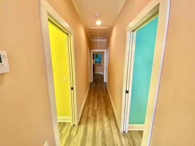 a hallway with yellow and blue doors and wood floors at Venture Out 152 Gulf Loop With Golf Cart in Panama City Beach