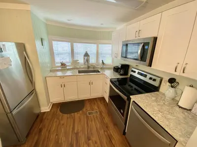 a kitchen with white cabinets and a stainless steel refrigerator at Venture Out 646 Octopus Dr Comes WITH GOLF CART in Panama City Beach