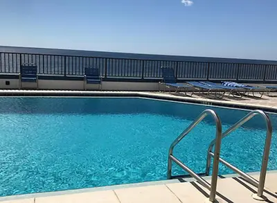 a swimming pool with blue water and some chairs at Aquavista 504W in Panama City Beach