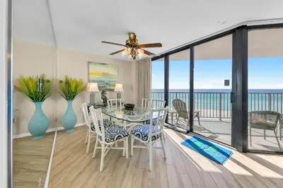 a dining room with a glass table and a balcony at Aquavista 504W in Panama City Beach