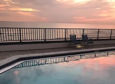 a swimming pool with two chairs and the ocean at Aquavista 504W in Panama City Beach