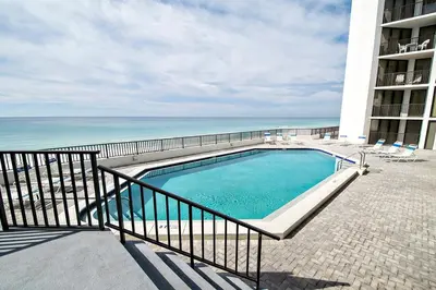 a swimming pool next to a balcony with the ocean at Aquavista 504W in Panama City Beach
