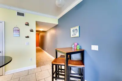 a hallway with a table and stools in a room at PCB Condo with Resort Amenities and Ocean Views in Panama City Beach