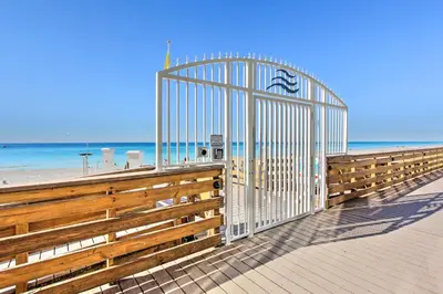 a gate on a beach with the ocean behind it at PCB Condo with Resort Amenities and Ocean Views in Panama City Beach