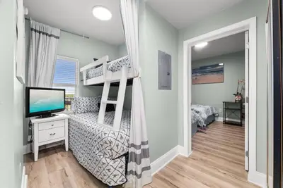 a bedroom with a bunk bed with a desk and a television at Beach & Ocean Views! Steps to Beach & Dining, Sleeps 9! Dolce Vita Getaways PCB in Panama City Beach