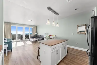an open kitchen and living room with a refrigerator at Beach & Ocean Views! Steps to Beach & Dining, Sleeps 9! Dolce Vita Getaways PCB in Panama City Beach