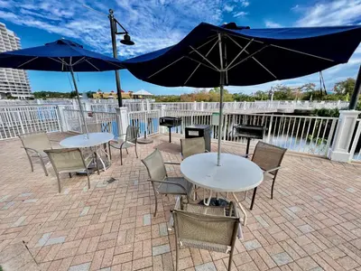 two tables and chairs with umbrellas on a patio at Beach & Ocean Views! Steps to Beach & Dining, Sleeps 9! Dolce Vita Getaways PCB in Panama City Beach